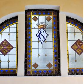 Windows with decorative polychrome glasses and with the monogram of the Sant'Elia family